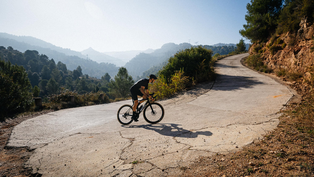 cyclist riding upa a switchback dressed in black wearing classic black cycling socks from nologo