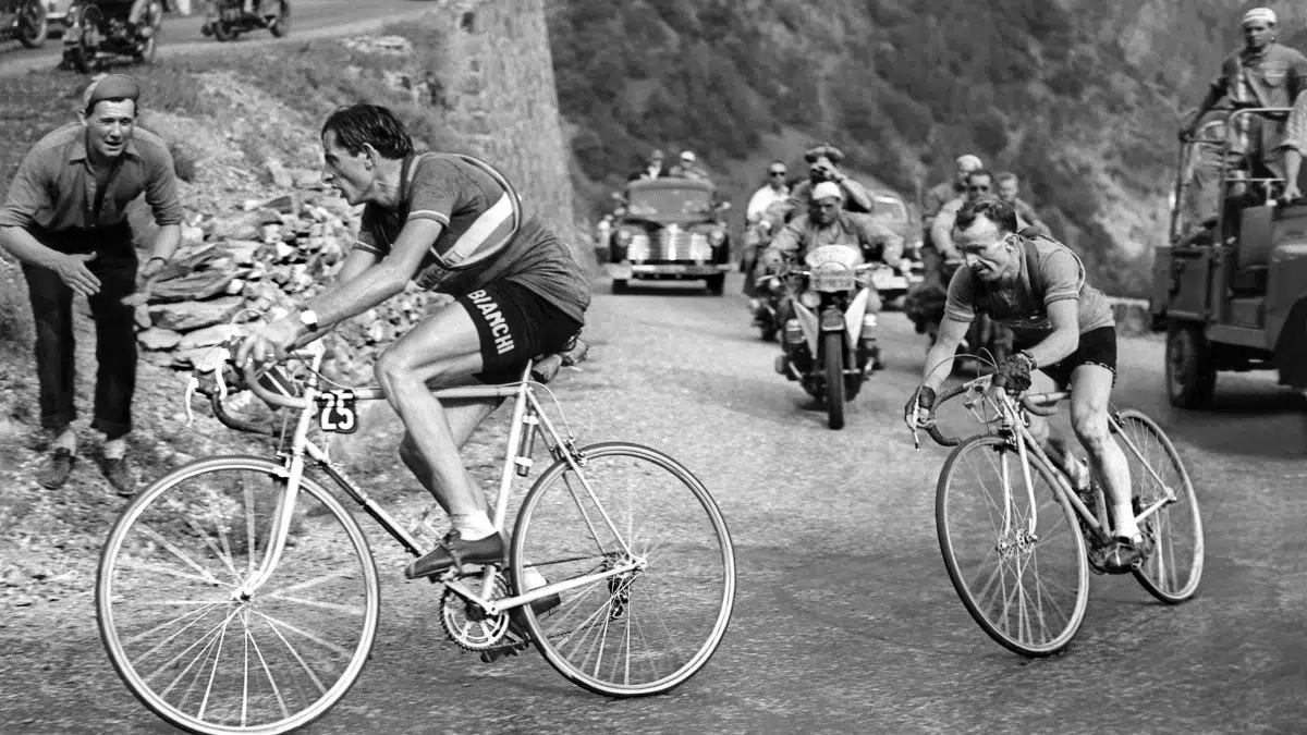 Vintage cycling race with two cyclists climbing a mountain road, emphasizing the role of quality cycling socks for performance and comfort.